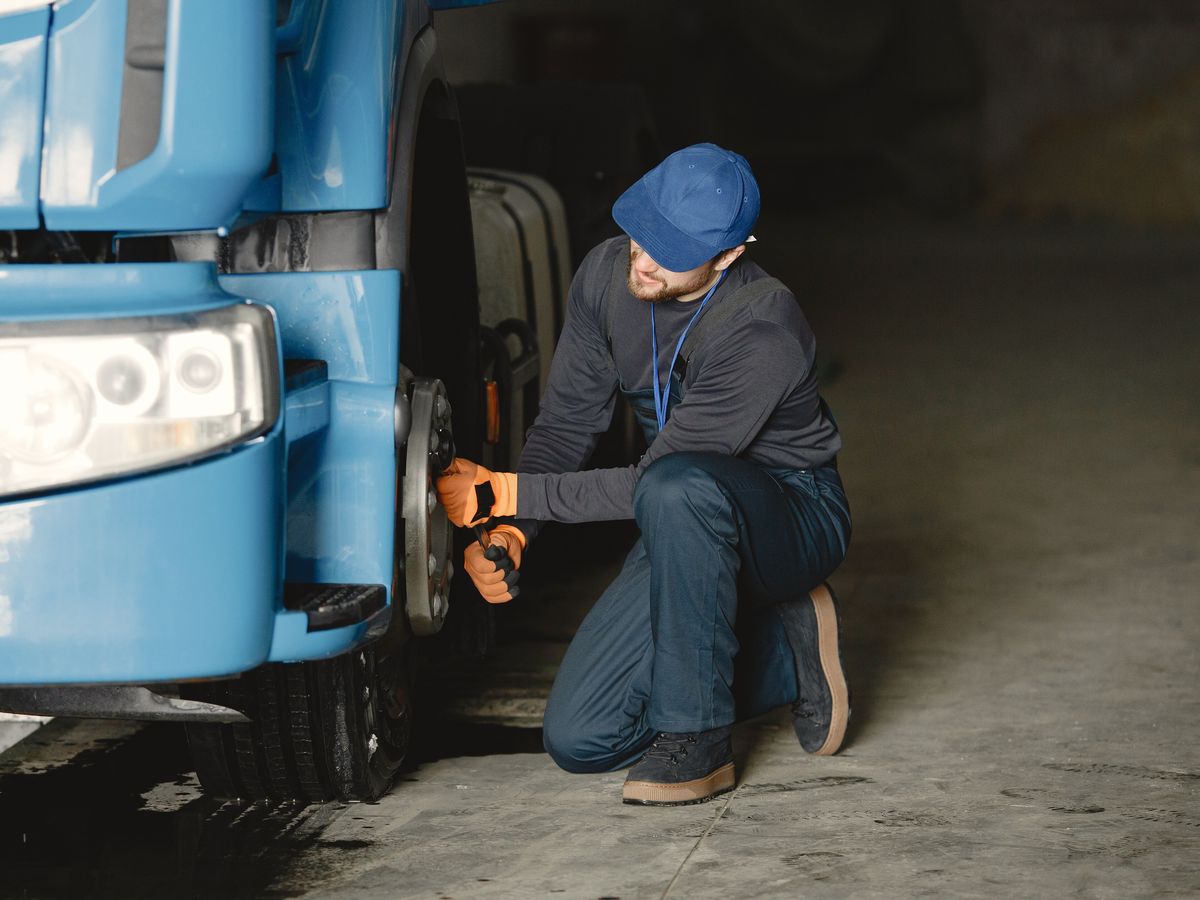 Mechanic loosening the lug nuts on a truck wheel with a wrench
