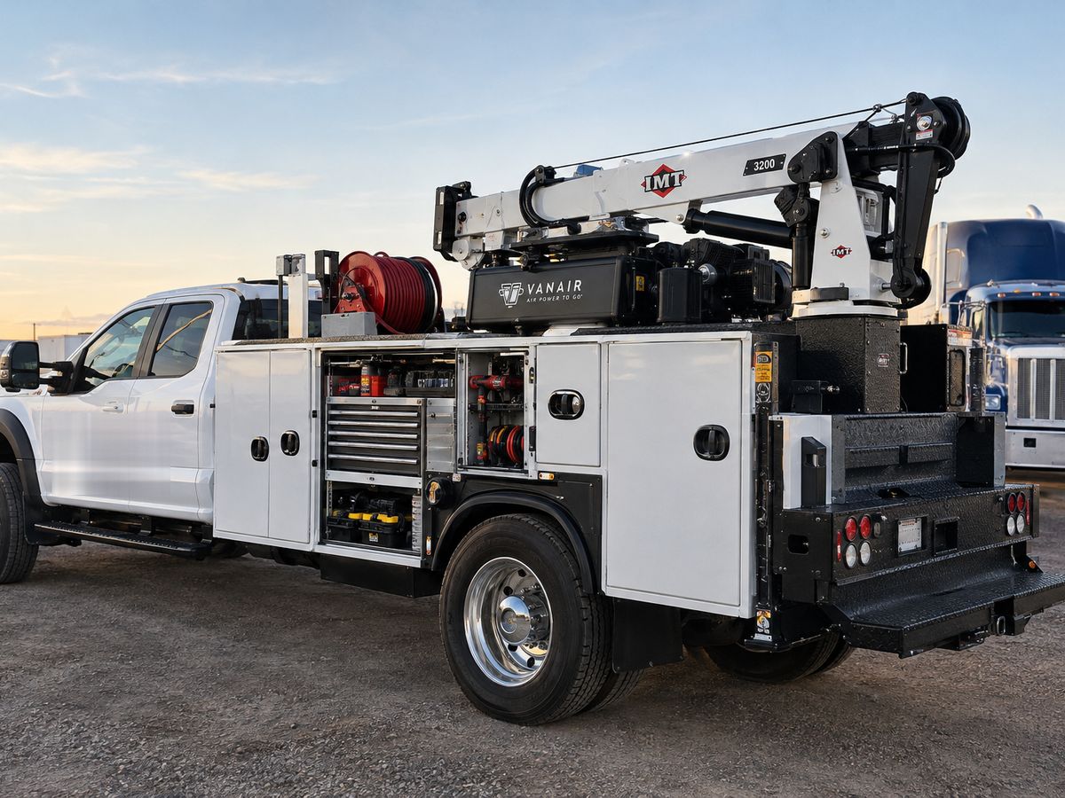 Mobile diesel service truck with a crane, air compressor, and open tool compartments parked in a truck yard